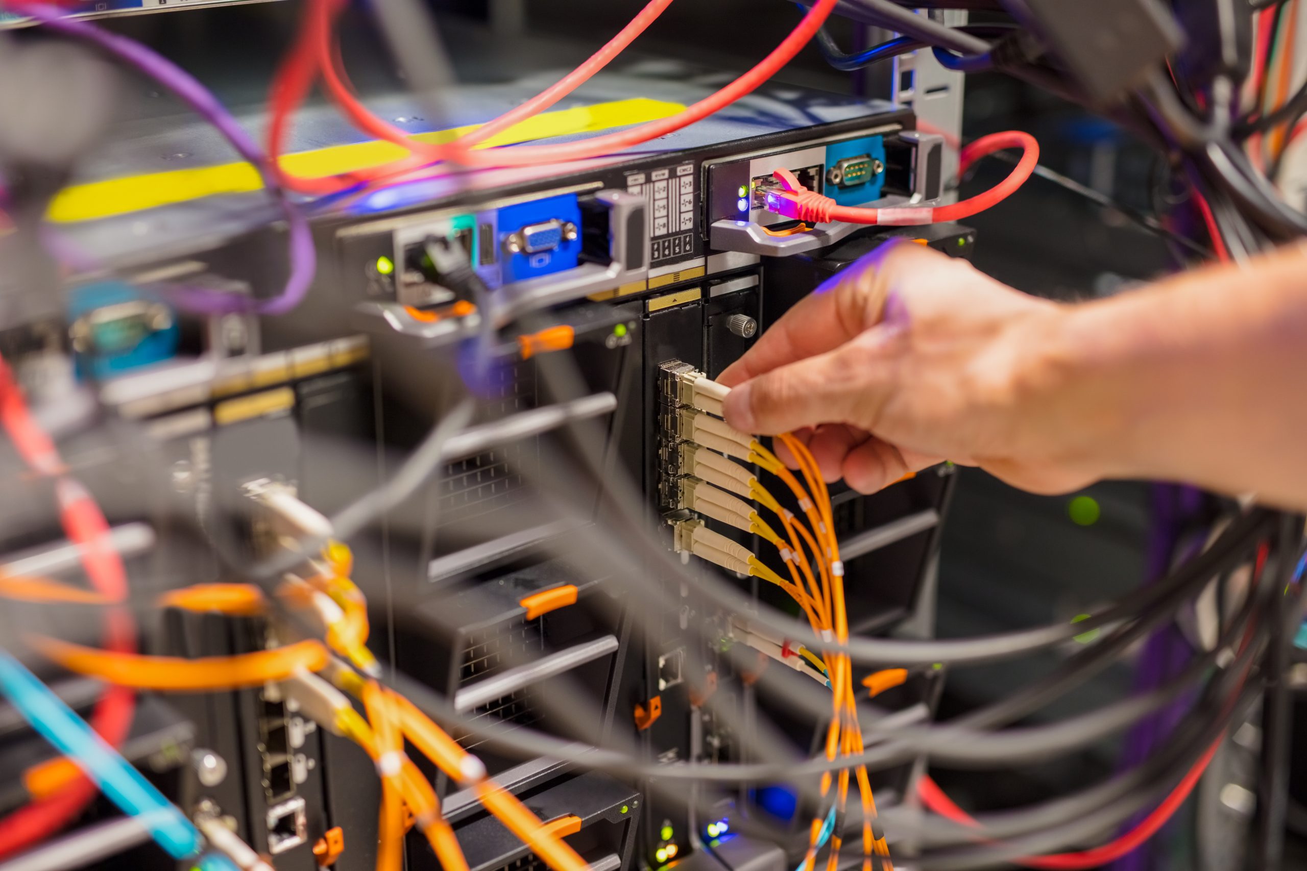 Closeup of IT consultant connecting network cable into switch in datacenter